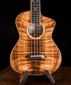 a wooden guitar sitting on top of a table next to a black background with the strings still attached