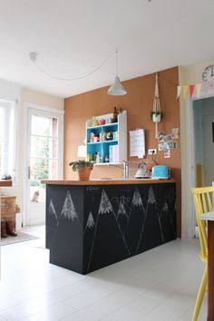 a kitchen with an island in the middle and yellow chairs at the counter, next to a dining room table