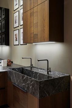 a kitchen with marble counter tops and wooden cabinetry, along with framed pictures on the wall