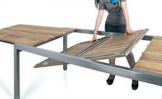 a woman standing on top of a wooden table next to a metal frame and wood planks