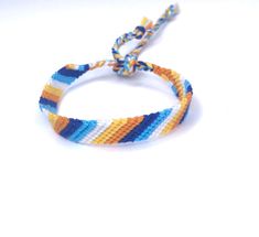 an orange, blue and yellow bracelet on a white surface with a string attached to it