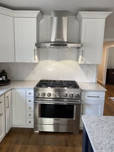 a stove top oven sitting inside of a kitchen next to white cabinets and counter tops