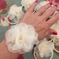 a close up of a person's hand with flowers and pearls on the wrist