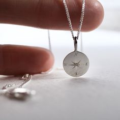 a person is holding a compass necklace in their hand