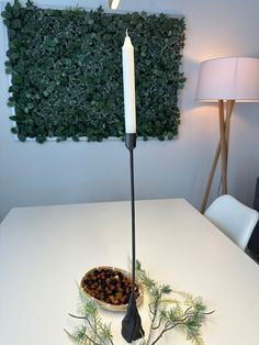 a white table topped with a bowl filled with food and a lit candle on top of it