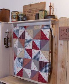 a cabinet with a quilt hanging from it's side and some other items on top