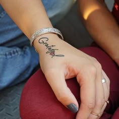 a woman's hand with a tattoo on her left wrist and the word grace written in cursive writing