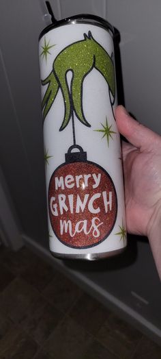 a person holding up a christmas can with the words merry grinch mas on it