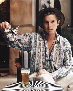 a man sitting at a table with a drink in his hand and an object on the table