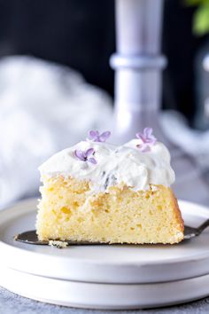 a piece of cake with white frosting and purple flowers on it sitting on a plate