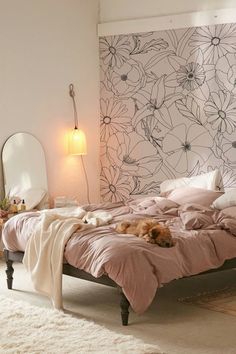 a dog laying on a bed in a room with a floral wallpaper behind it