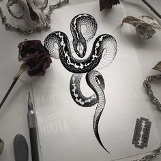 a drawing of a snake on top of a piece of paper next to some flowers