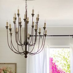 a chandelier hanging from the ceiling in front of a window with pink flowers