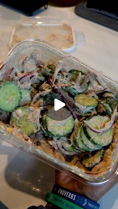 a glass dish filled with cucumbers and other food on top of a table