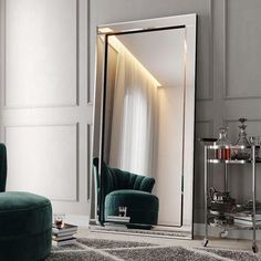 a large mirror sitting on top of a floor next to a green chair and ottoman