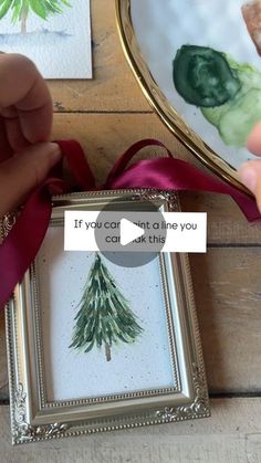 someone is holding a christmas card in front of a mirror with a red ribbon around it