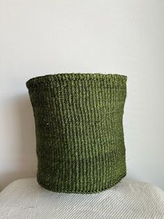 a green basket sitting on top of a white pillow