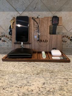 an apple watch and other electronic gadgets sit on a wooden tray in front of a tiled wall