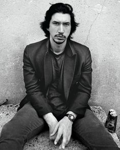 a man sitting on the ground next to a wall with a beer in his hand