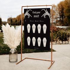 a sign that is on the side of a road near some grass and flowers in a vase