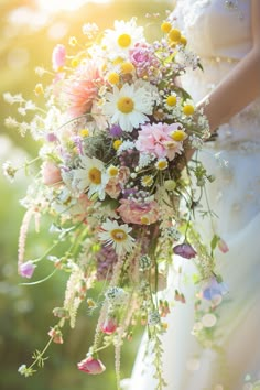 a bride holding a bouquet of flowers in her hand with the sun shining behind her