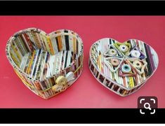 two heart shaped boxes filled with books on top of a pink surface