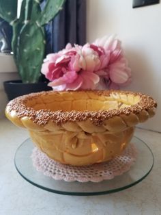 a bowl sitting on top of a glass plate next to a potted plant and pink flowers