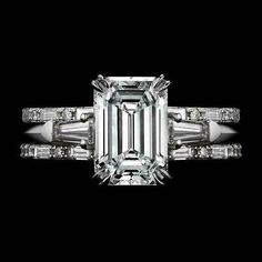 an emerald - cut diamond ring with baguetts on the shoulders and side stones