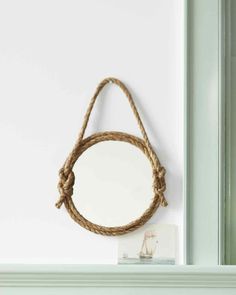 a rope hanging from the side of a wall next to a mirror on a shelf