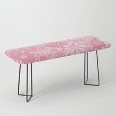 a pink bench sitting on top of a metal frame stand with flowers on the back