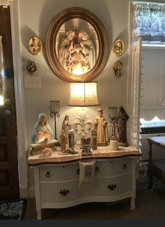 a white dresser topped with lots of figurines and lights next to a mirror