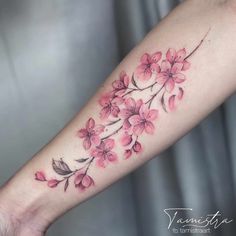 a woman's arm with pink flowers and leaves on the left side of her arm