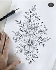 a woman's hand holding a pen and drawing flowers on white paper with black ink