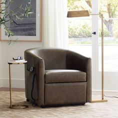 a brown chair sitting in front of a window next to a table with a lamp on it