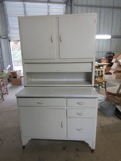 an old white kitchen cabinet in a garage