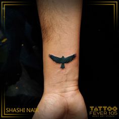 a small black bird tattoo on the wrist