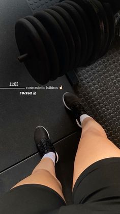 a person standing next to a weight machine with their feet on the ground and an exercise bar in front of them