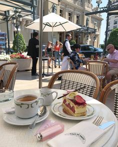 a table topped with plates of food and cups of coffee next to an umbrella covered patio