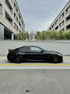 a black car parked on the side of a road in front of two tall buildings