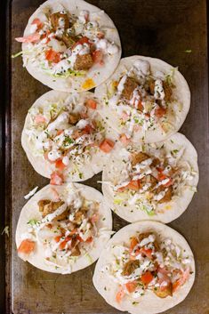 six tacos with meat, cheese and vegetables on a baking sheet