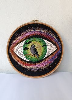 an embroidery art piece with a bird on it's eye