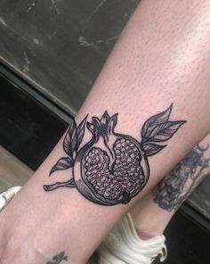 a pomegranate tattoo on the left arm and wrist is shown in black ink