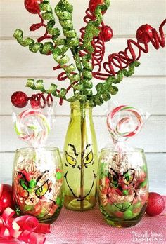 three glass vases with candy in them sitting on a table next to christmas decorations