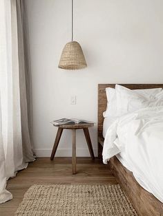 a bed with white sheets and pillows in a room next to a lamp hanging from the ceiling