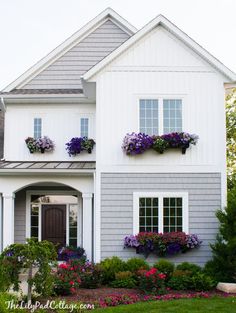 a house with flowers in the window boxes on the front and side of the house