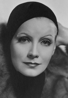 black and white photograph of a woman wearing a fur coat with her hands on her head