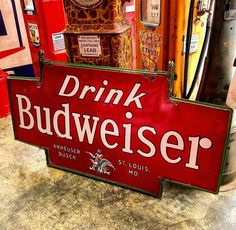 a red drink budweiser sign sitting on top of a counter