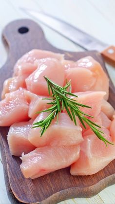 raw fish fillets on a wooden cutting board with rosemary sprig in the center