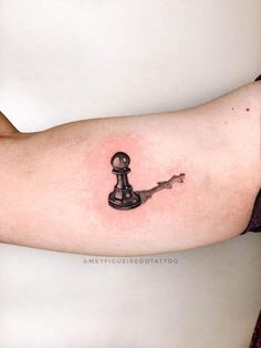 a person's arm with a black and white chess piece tattoo on it