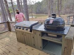 a man standing next to an outdoor grill on a deck